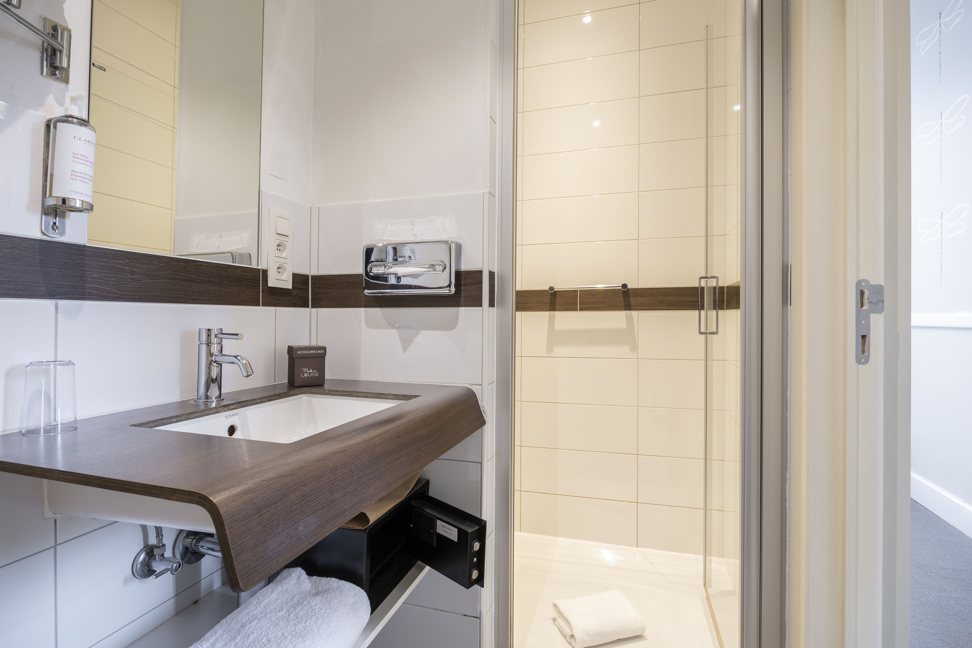 Un baño moderno con tocador de madera, lavamanos y cabina de ducha de vidrio.