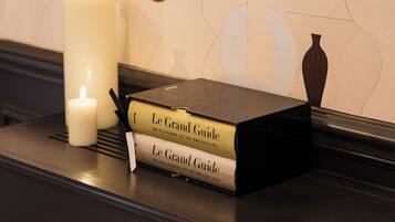 Une bibliothèque avec deux livres intitulés « Le Grand Guide » et une bougie allumée.