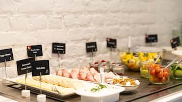 Ein reichhaltiges Buffet mit verschiedenen Speisen, darunter Käse, Schinken und Obst.
