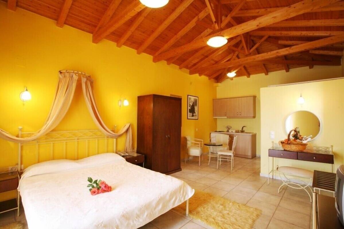 A bedroom with a bed, a wooden wardrobe, a desk with a chair, and a vanity with a mirror.