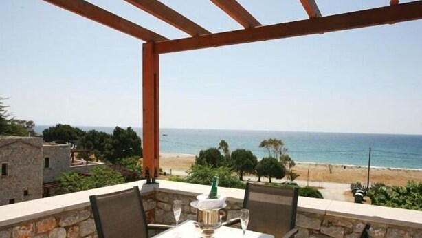Een balkon met een tafel en stoelen met uitzicht op een strand.
