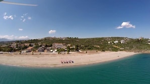 Een kustplaatsje met een strand, huizen en een heldere lucht.