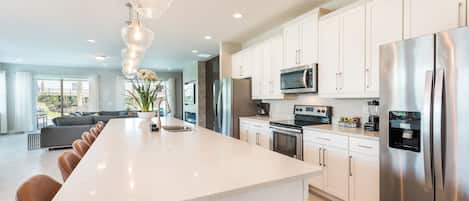 A modern kitchen with white cabinets, stainless steel appliances, and a large island with seating.