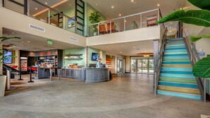 A spacious lobby with a central reception desk, a staircase, and a view of the outside. - Encore Resort and Water Park at Reunion by Rentyl (Kissimmee)