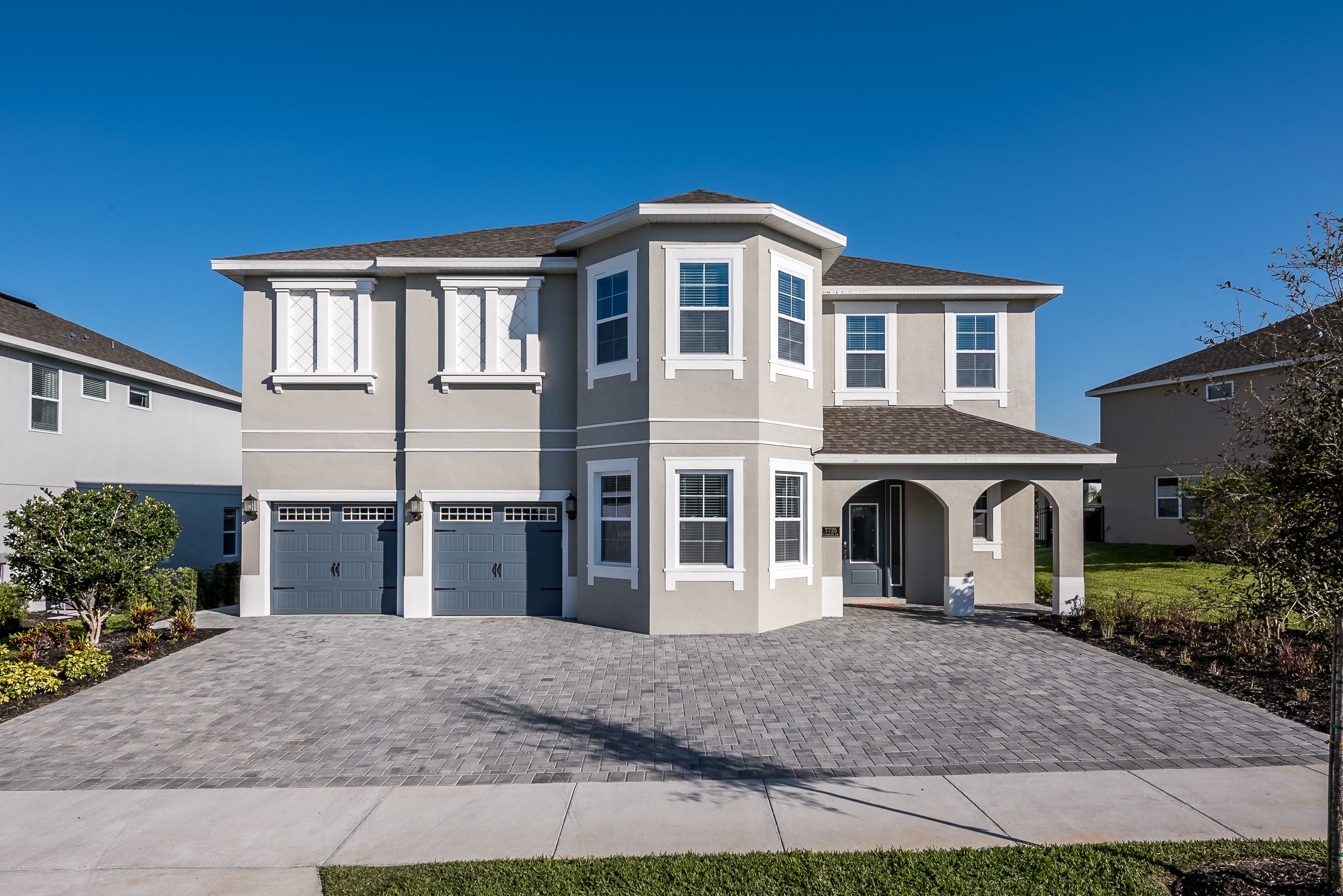 A two-story residential building with a garage, a covered entryway, and a landscaped driveway.