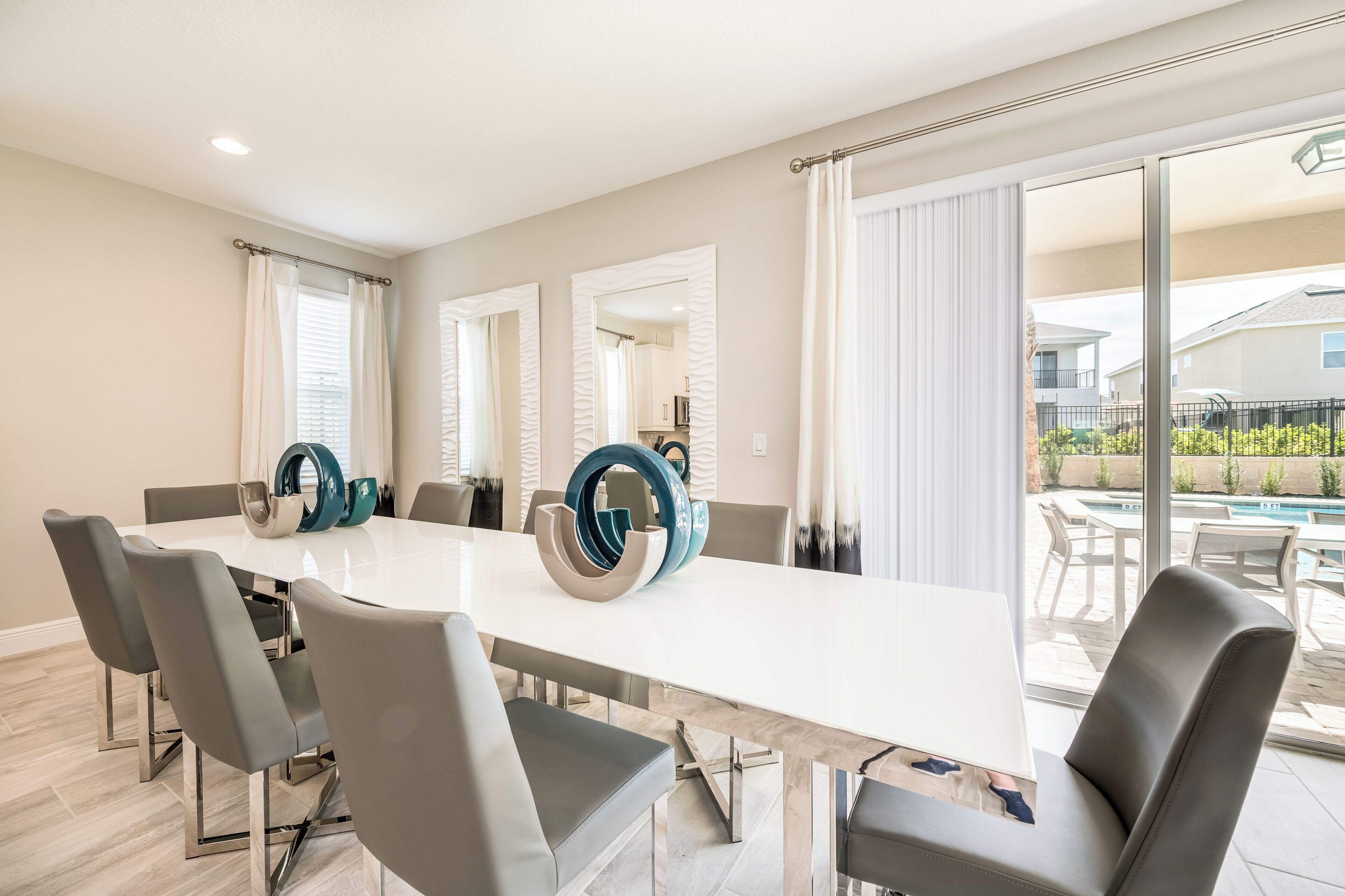A modern dining area with a large table, grey chairs, and decorative vases.