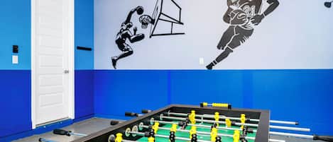A foosball table in a room with blue walls and a white door.