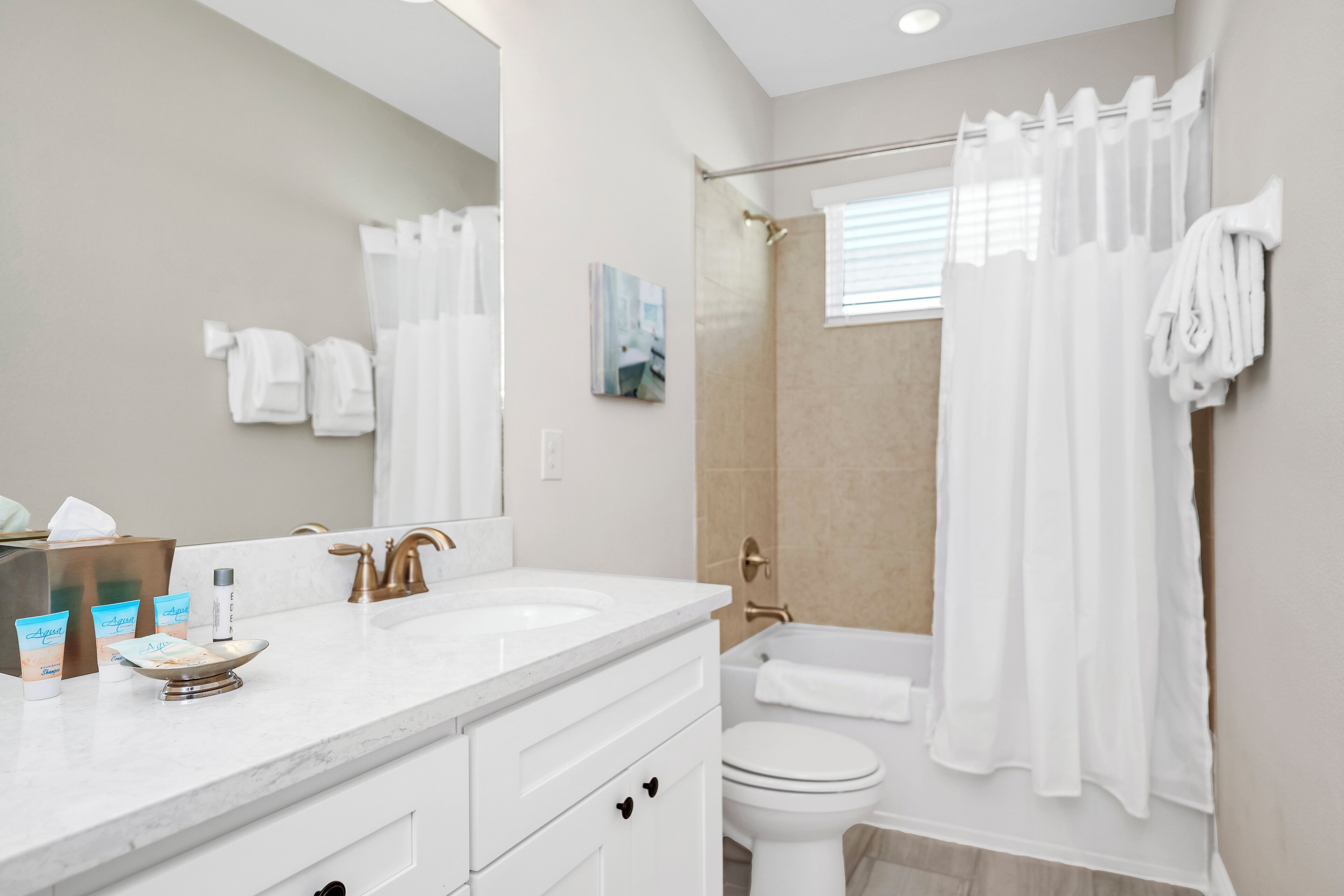 Une salle de bain moderne avec un meuble-lavabo blanc, un grand miroir, une baignoire et des toilettes.