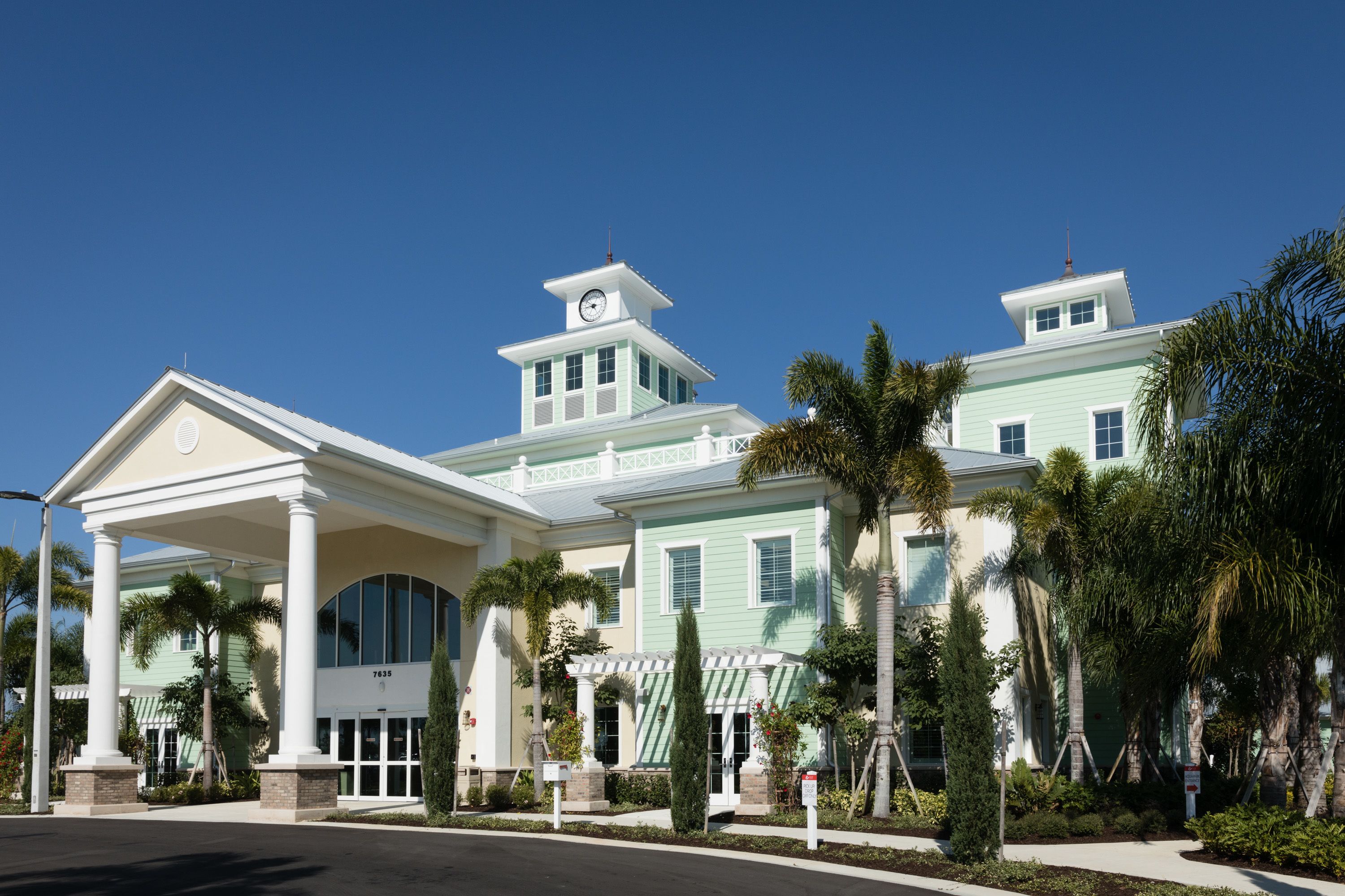 A large, two-story building with a central entrance, multiple windows, and a clock tower.