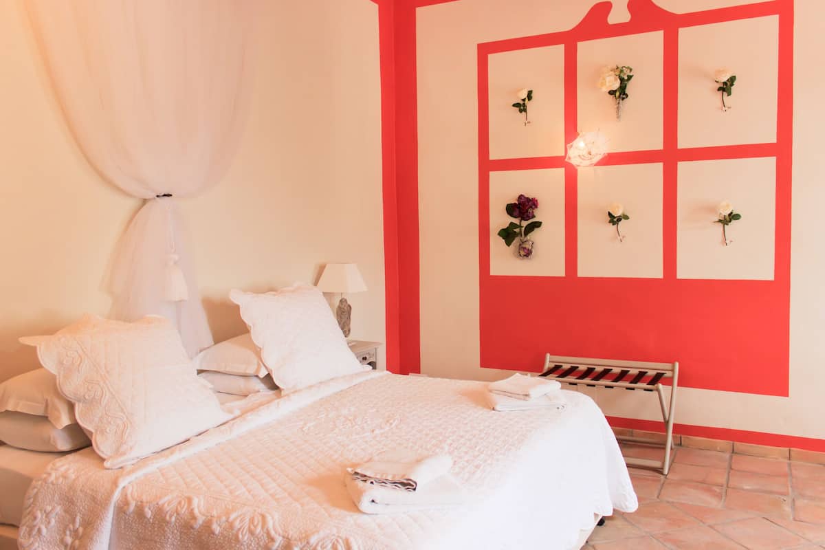 Un dormitorio con una cama grande, un banco y una pared decorada con cuadros.