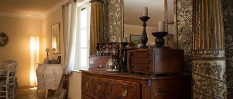 Una habitación con un aparador de madera, un espejo y una ventana con cortinas.
