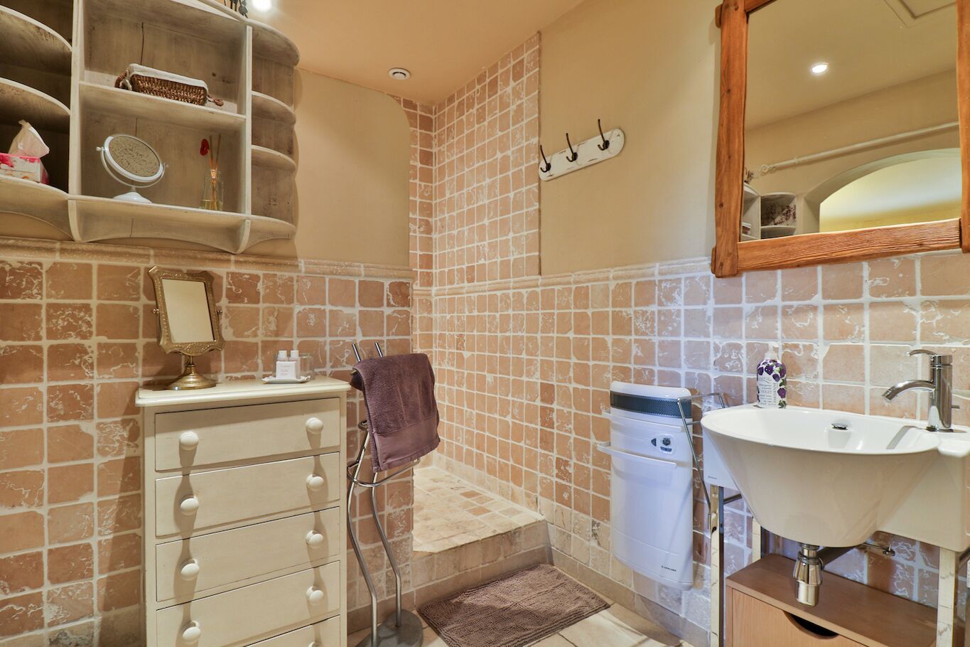 A bathroom with a sink, mirror, towel rack, and storage shelves.