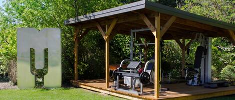 An outdoor gym with exercise equipment, a covered seating area, and a large 'U' sculpture.