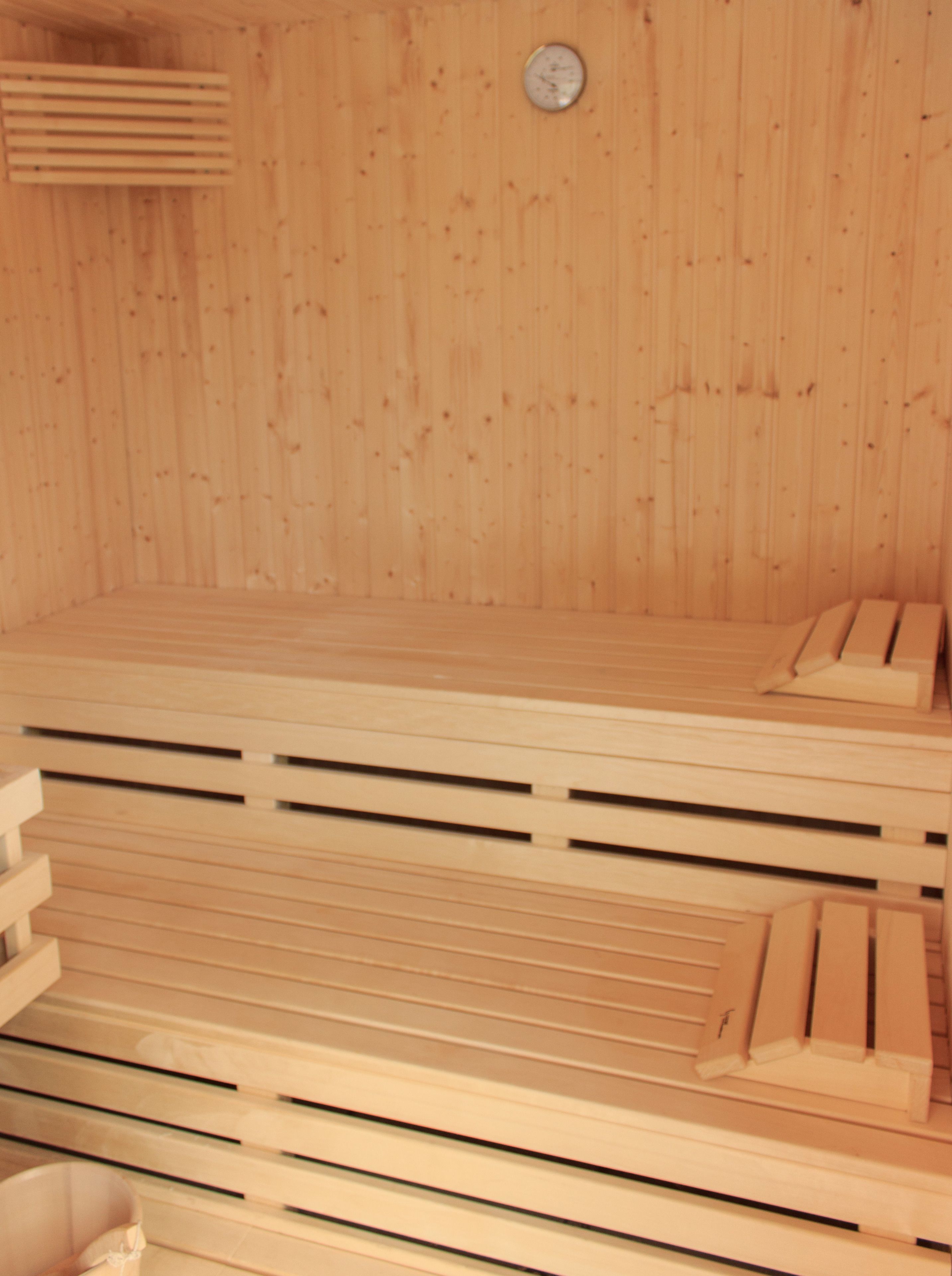 Eine Sauna mit Holzbänken und einem sichtbaren Temperaturanzeiger.