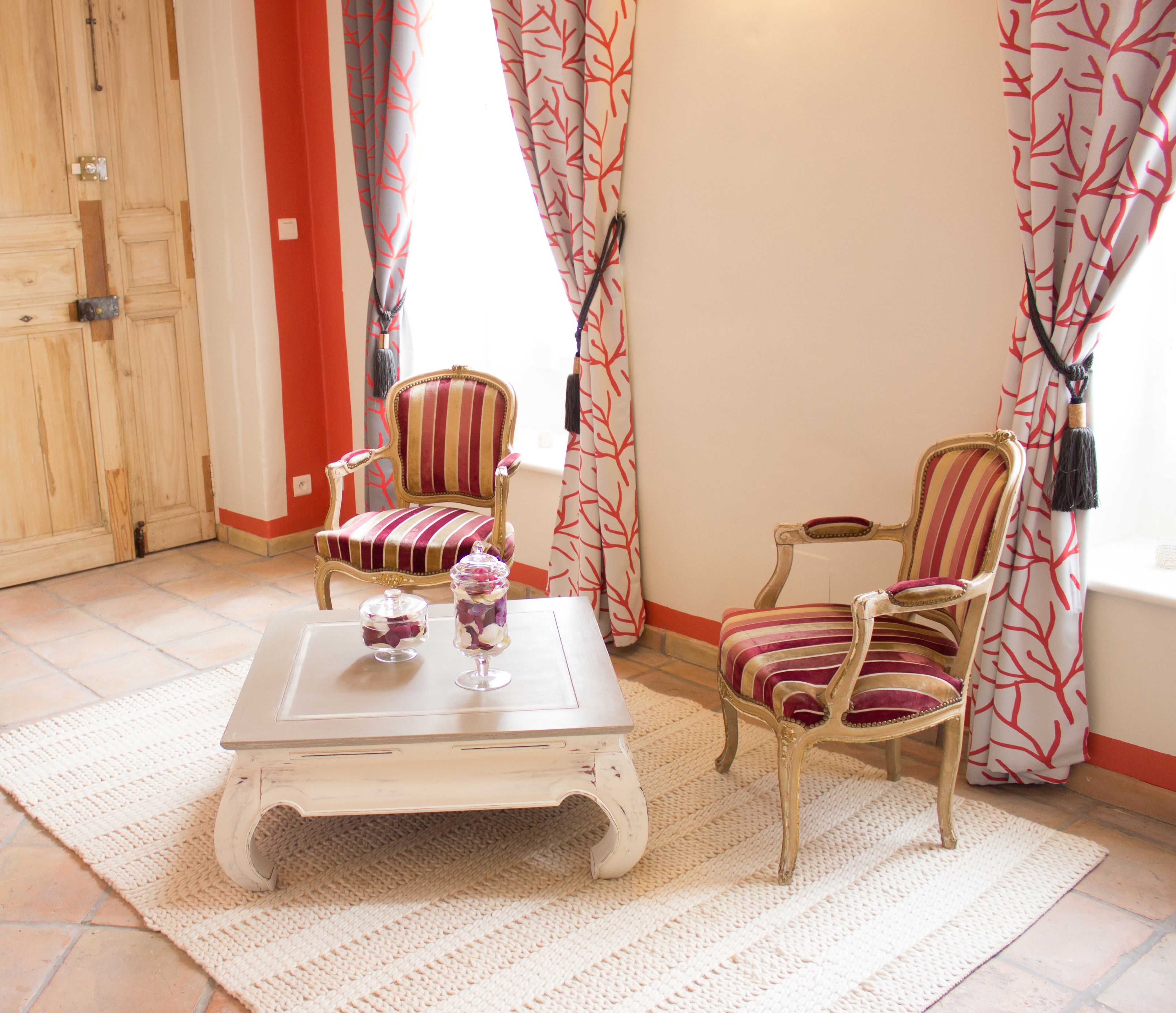 A room with two striped armchairs, a small white table, and a decorative vase.