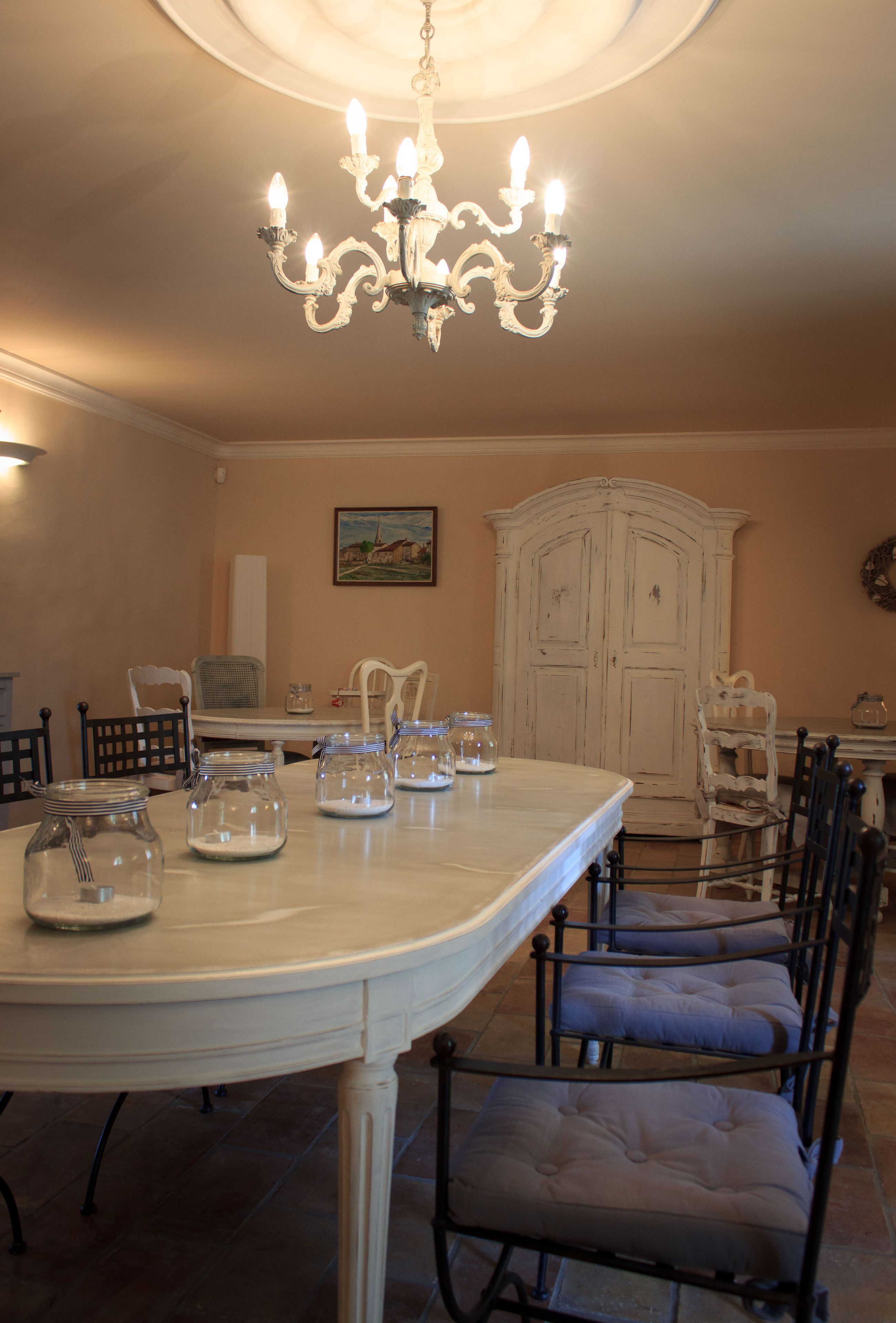 A dining area with a large table, chairs, a chandelier, and a cabinet.