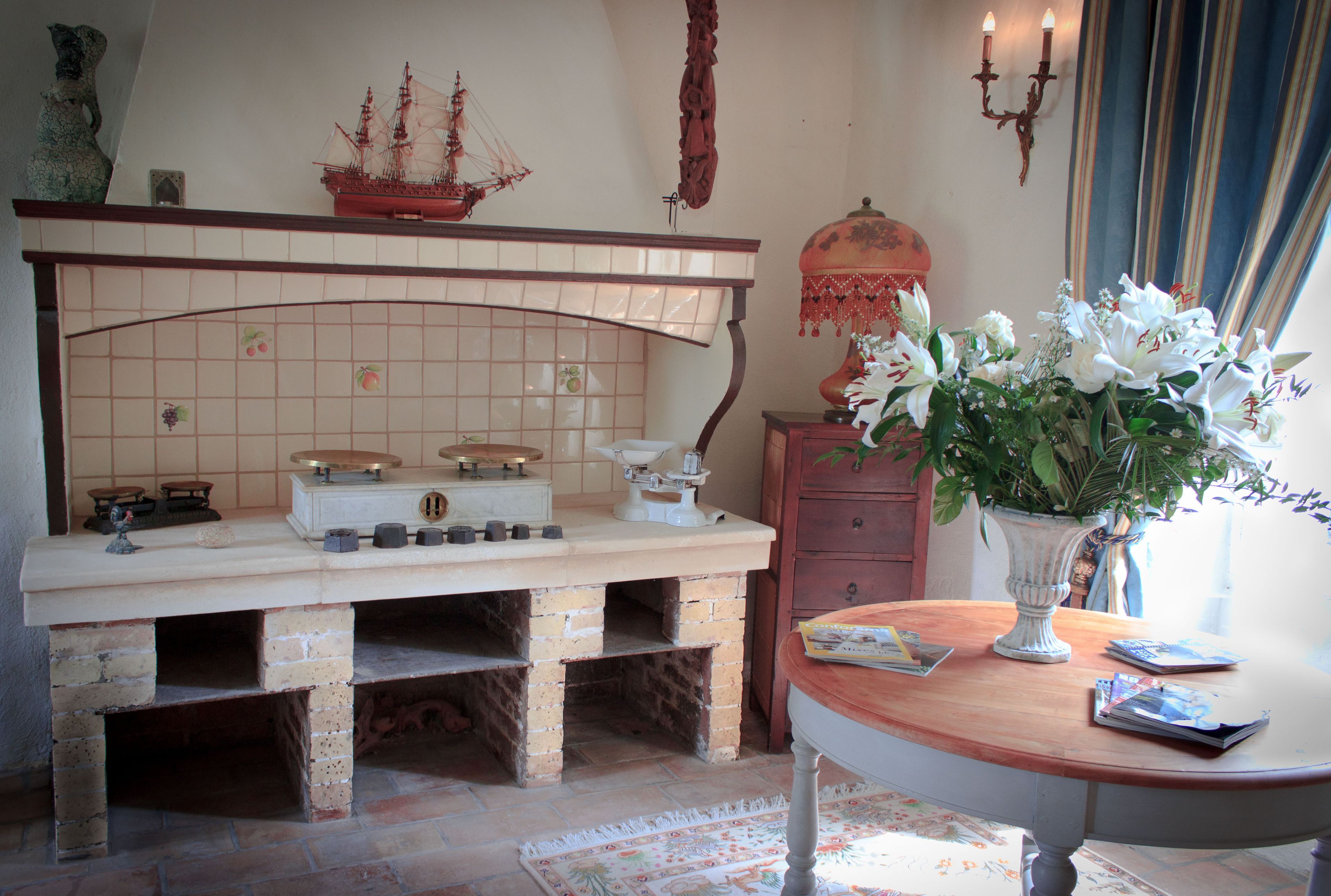 A kitchen with a brick stove, a tiled backsplash, and a wooden table with a vase of flowers.