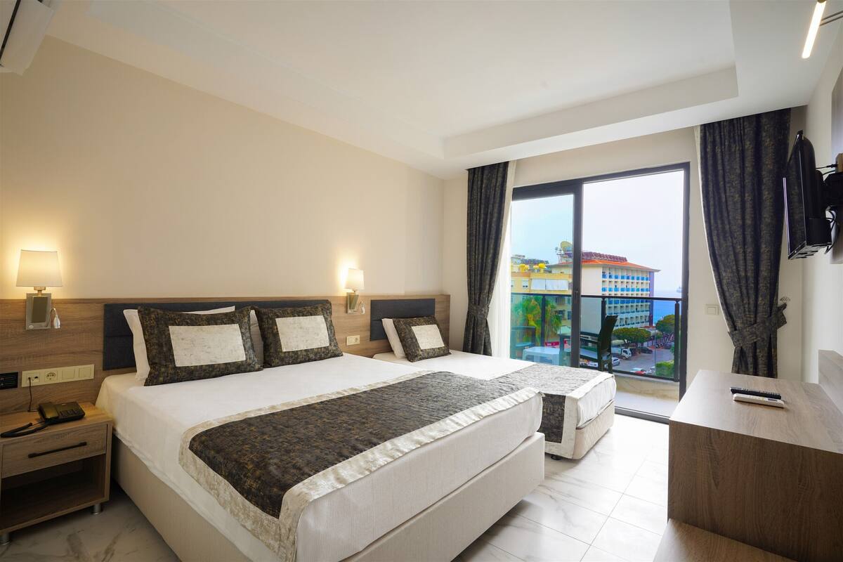 Una habitación de hotel con una cama grande, un escritorio, una silla y vistas a un edificio por la ventana.