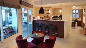 A modern interior with a bar area, seating, and a kitchen in the background. - Hôtel Au Bon Coin (Biarritz)