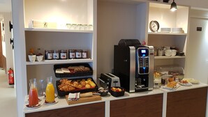 A breakfast bar with a coffee machine, juice dispensers, and a variety of pastries and bread. - Hôtel Au Bon Coin (Biarritz)