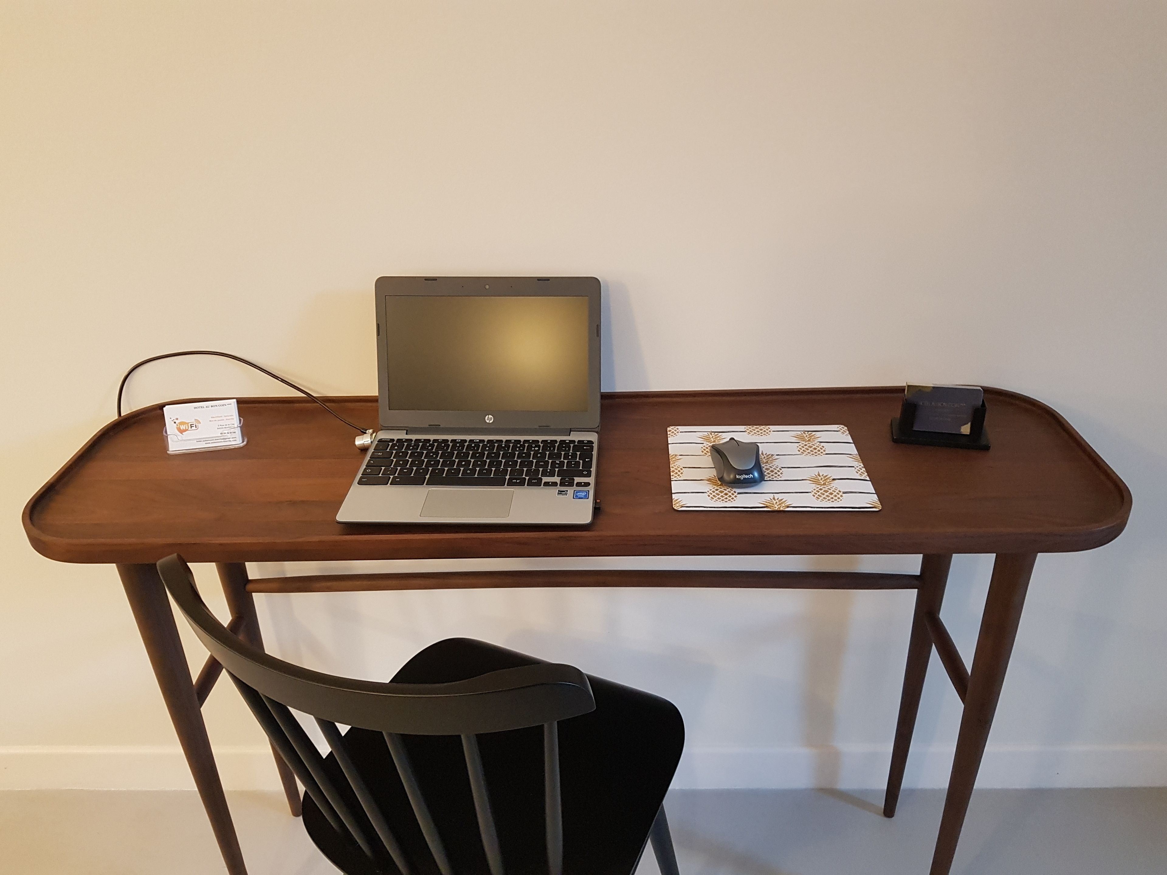 Un bureau en bois avec un ordinateur portable, une souris et un tapis de chargement sans fil.