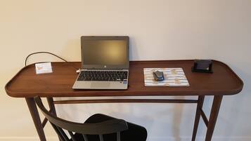 Un bureau en bois avec un ordinateur portable, une souris et un tapis de chargement sans fil.