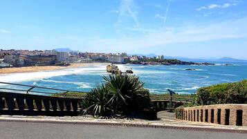 Un paysage urbain côtier avec une plage, des affleurements rocheux et un ciel dégagé.