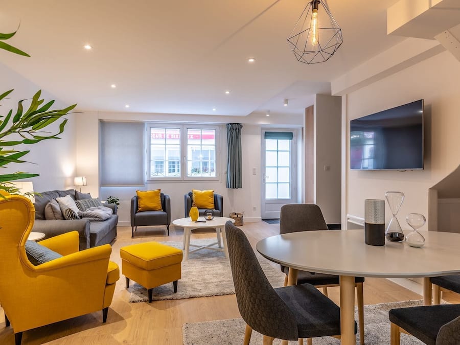 Una sala de estar moderna con sofá, sillones, una mesa de comedor y televisor.