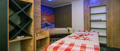 Una habitación con una cama, una repisa de madera, un mural y una lámpara en el techo.