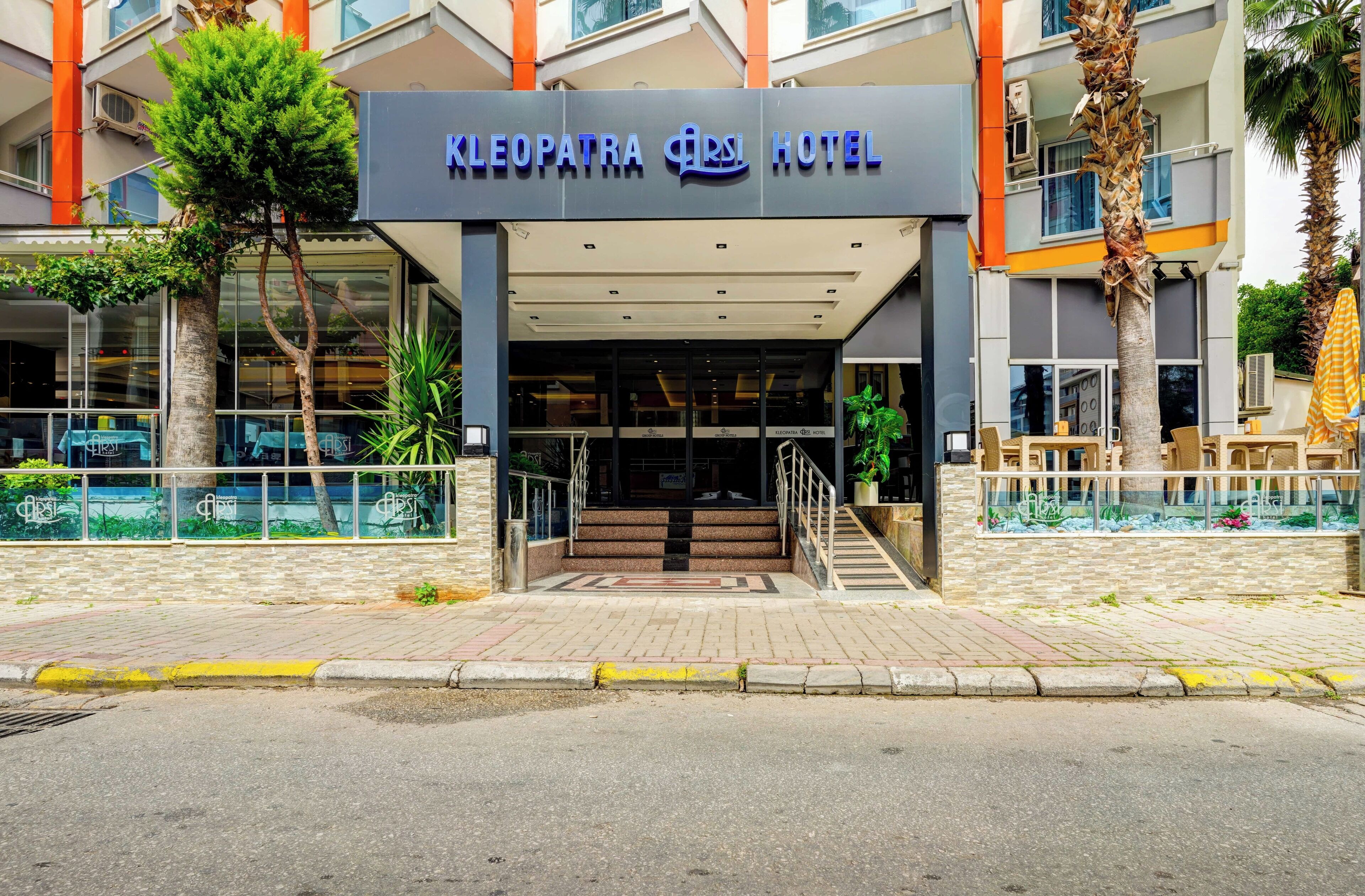 The entrance of Cleopatra City Hotel with a modern facade, glass doors, and a staircase leading to the entrance.