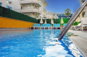 Una piscina al aire libre, sillones reclinables de piscina