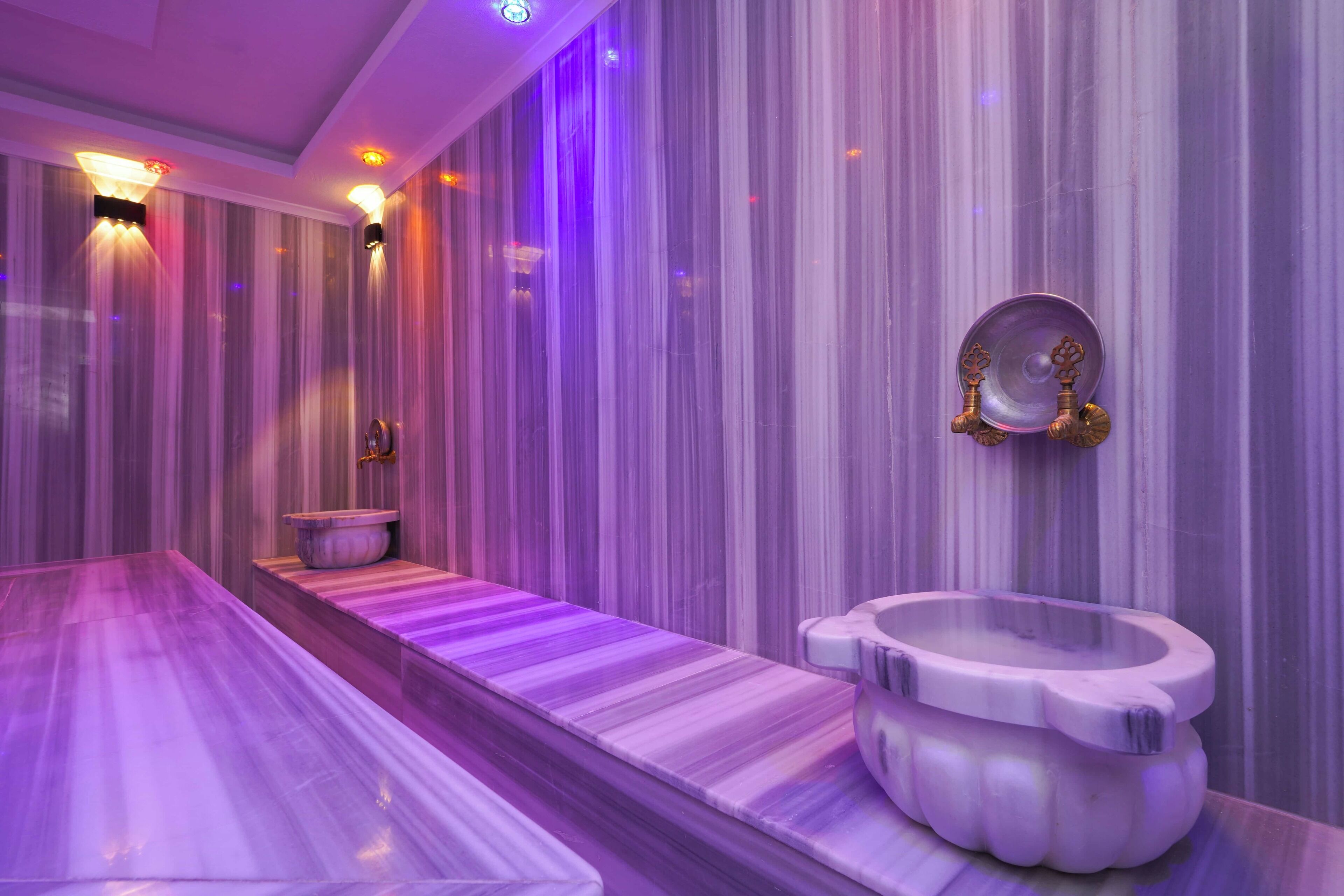 Ein modernes Badezimmer mit Marmorboden, einer freistehenden Badewanne und einem wandmontierten Waschbecken.