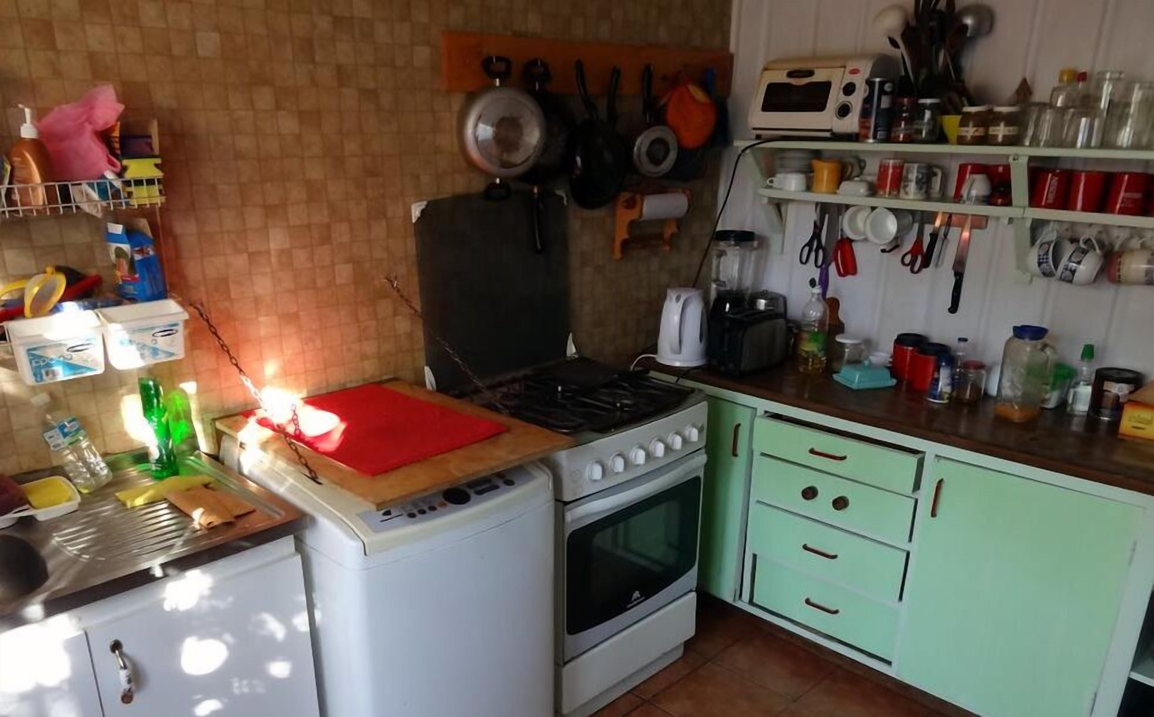 A compact kitchen with a gas stove, oven, and a microwave. There are various kitchen utensils and appliances on the walls and counters.