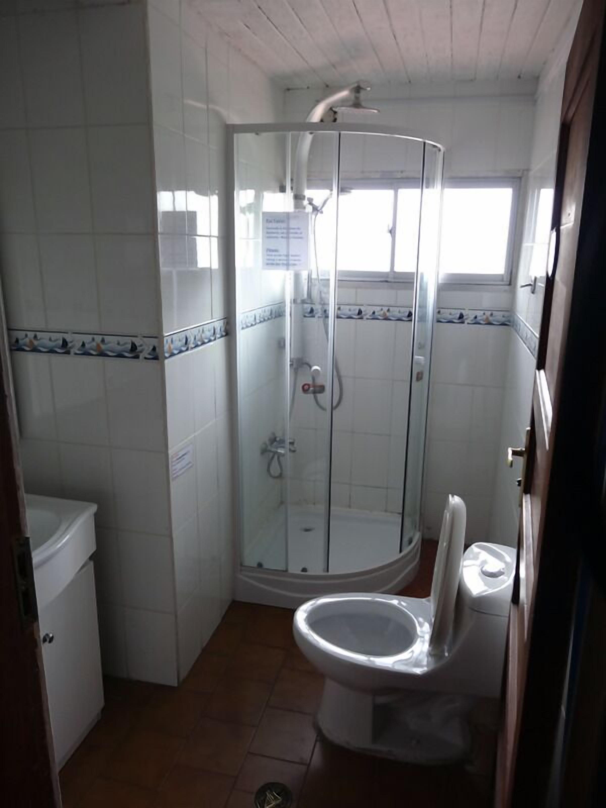 A bathroom with a glass-enclosed shower, a toilet, and a sink.