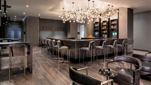 A modern bar area with a central island, bar stools, and a chandelier.