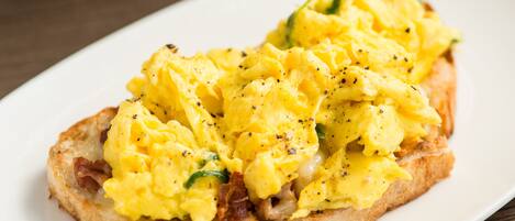 Scrambled eggs on toast with a side of bacon.