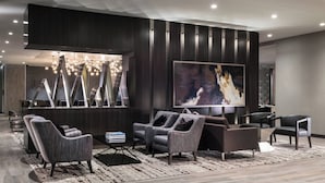 A modern living room with a large flat-screen TV, dark wood paneling, and contemporary furniture.
