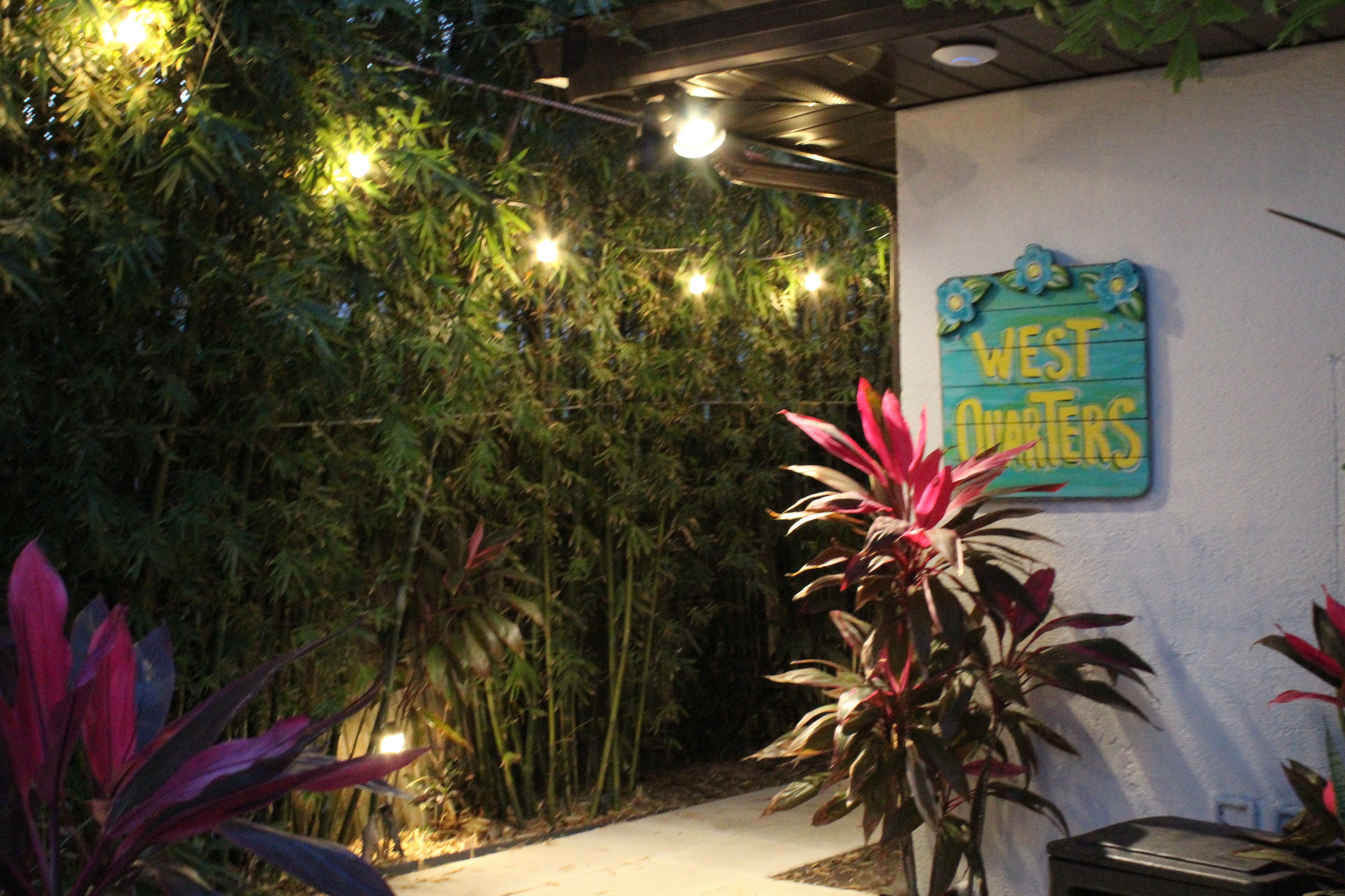 A garden area with bamboo plants, a sign reading "WEST QUARTERS," and a pathway leading to a building.