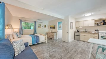 A compact living space with a bed, a sofa, a desk, a kitchenette, and a television.