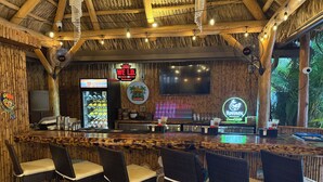 A bar area with a wooden ceiling, bar stools, and a neon sign. - Siesta Key Palms Resort (Sarasota)
