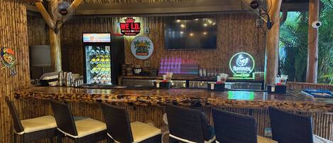 Un área de bar con techo de madera, taburetes y un letrero de neón.
