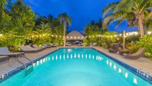 A swimming pool with lounge chairs and palm trees, surrounded by string lights. - Siesta Key Palms Resort (Sarasota)