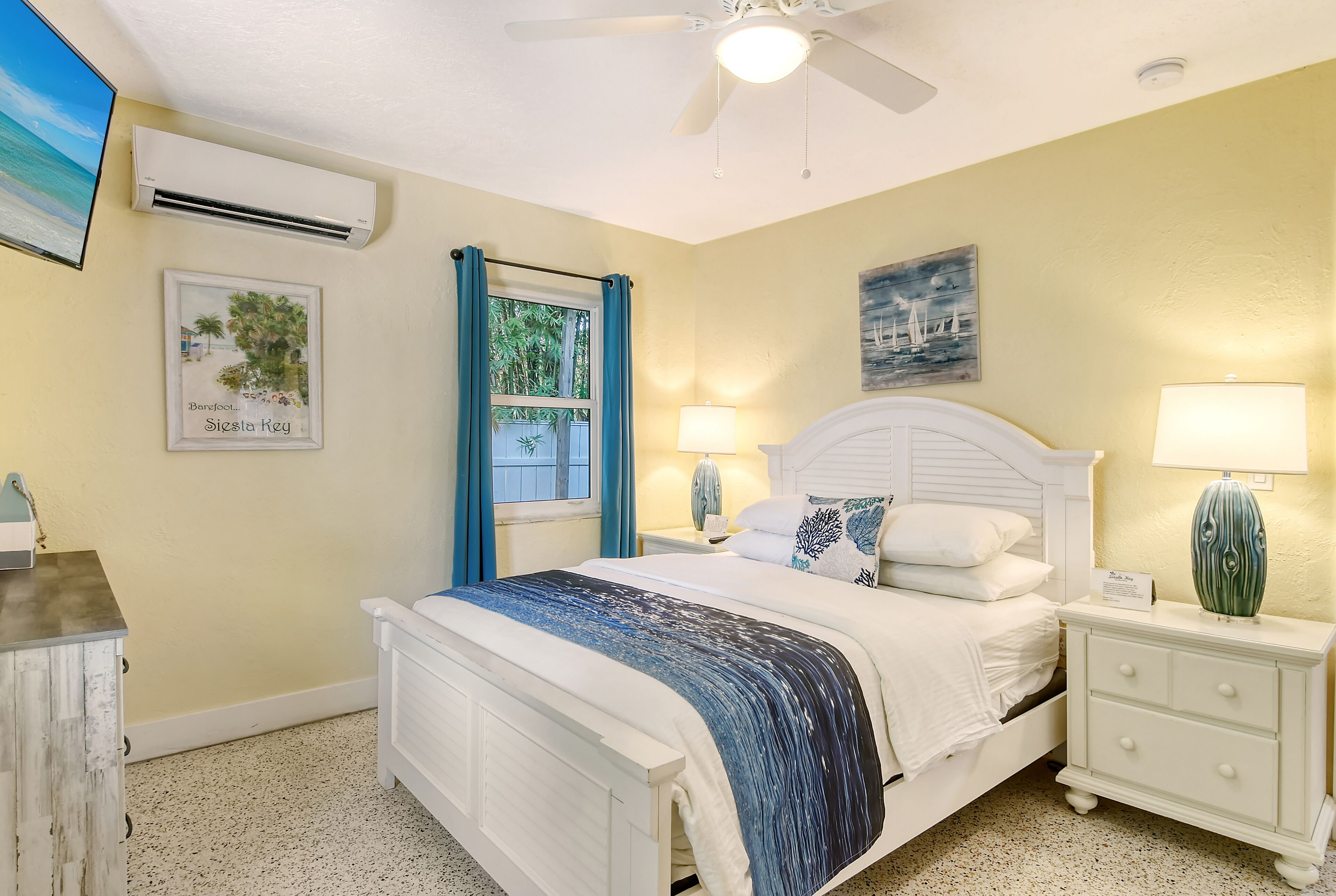 A bedroom with a bed, nightstands, a ceiling fan, and wall art.