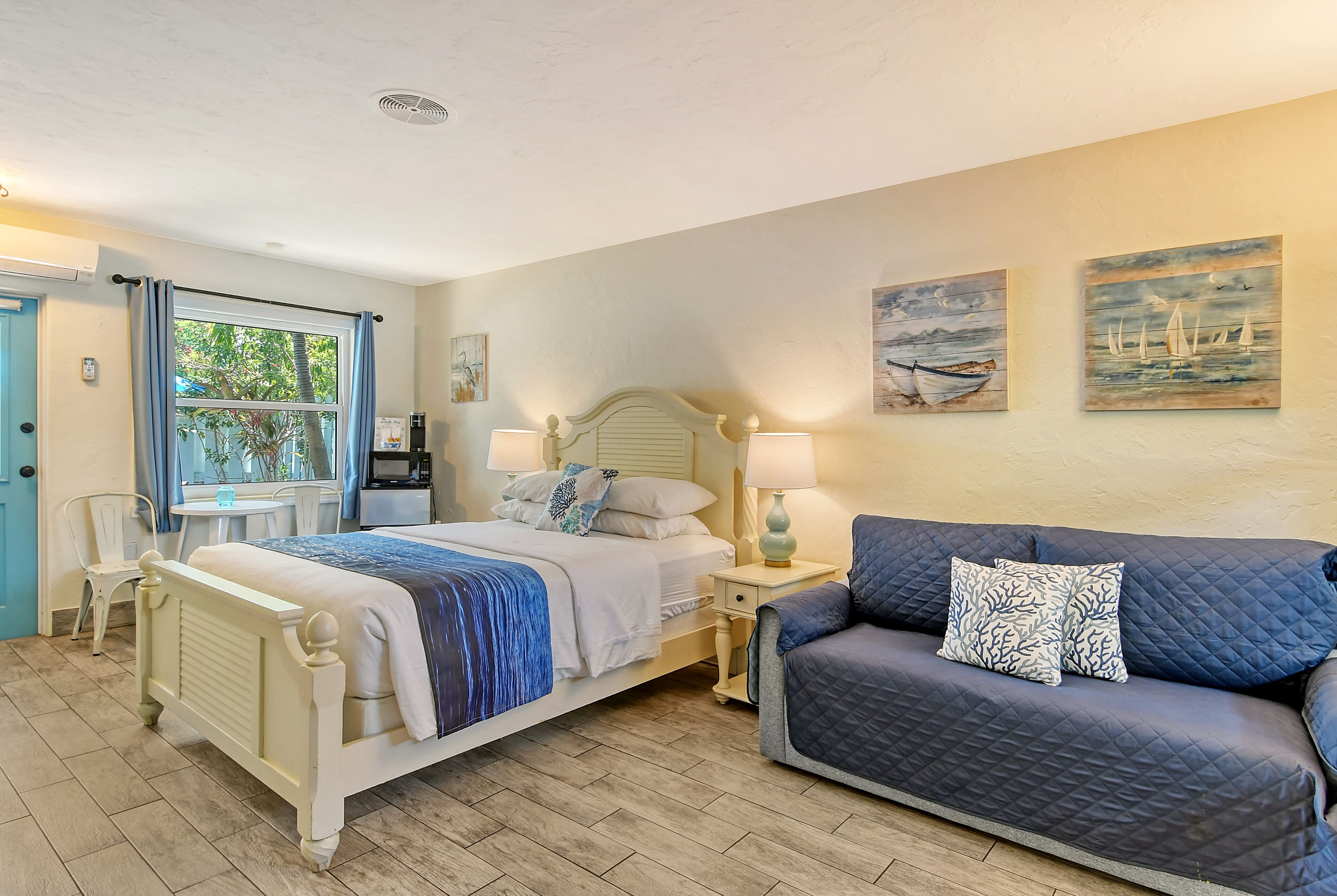 A bedroom with a bed, a sofa, a bedside table, a lamp, and a window with curtains.