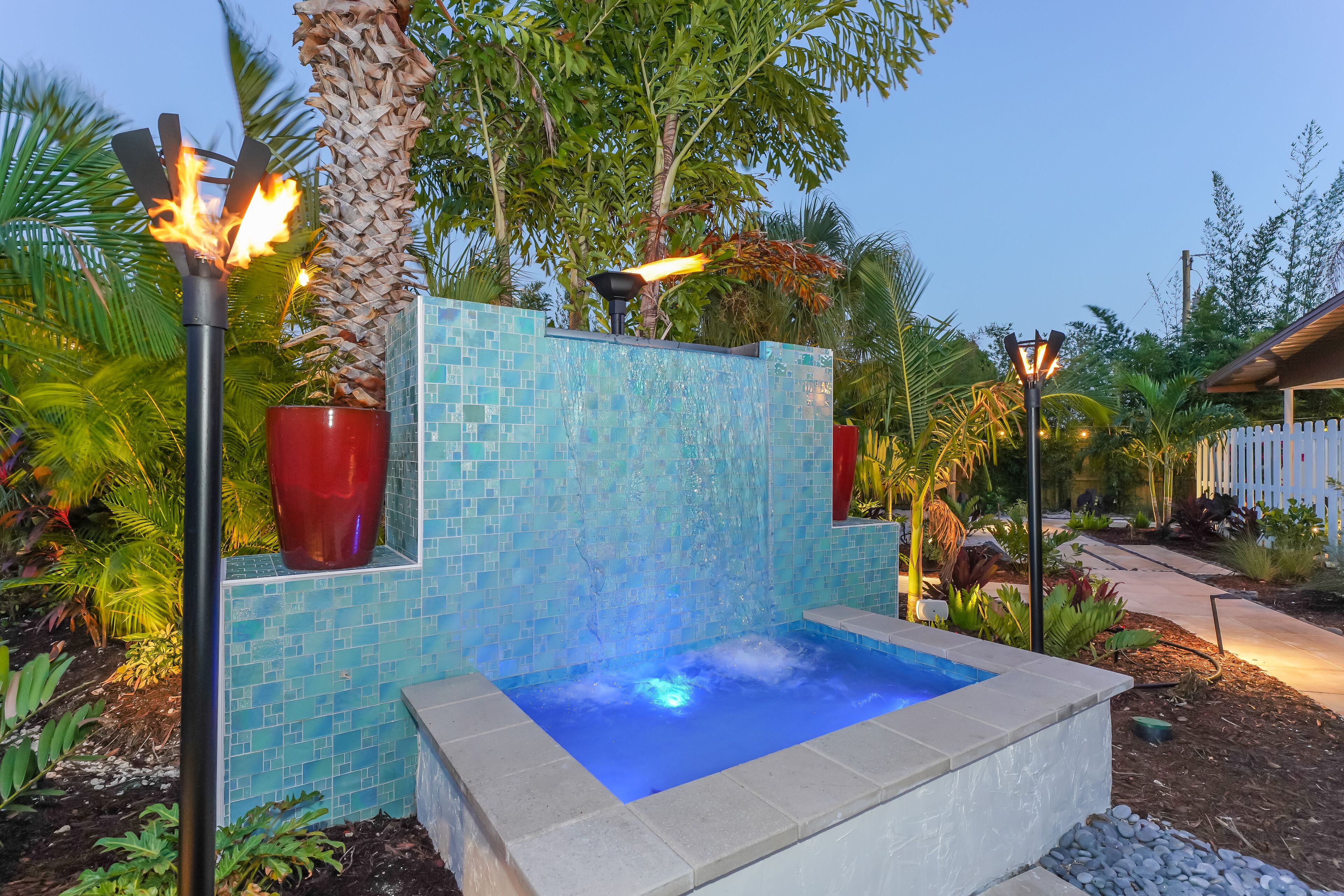 A hot tub with a tiled wall and a fire feature.