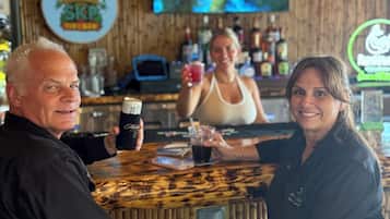 Un bar avec un décor intérieur en bois, un écran de télévision et diverses bouteilles exposées sur des étagères.