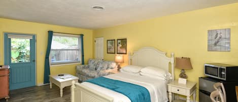 A bedroom with a bed, bedside tables, a chair, a microwave, and a refrigerator.