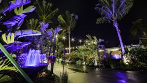 A nighttime view of a tropical resort with a water feature, palm trees, and ambient lighting. - Siesta Key Palms Resort (Sarasota)