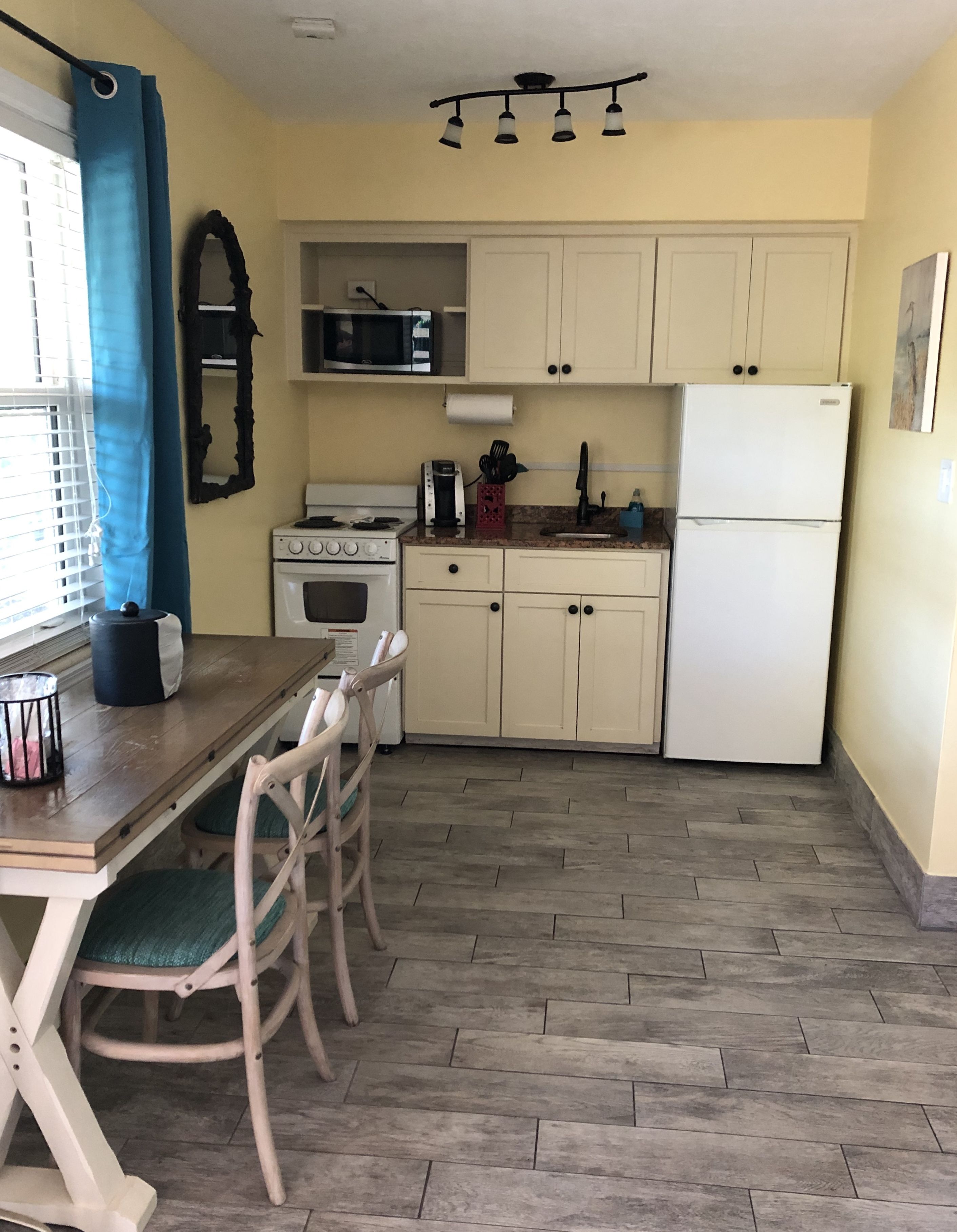 A compact kitchen with a dining table and chairs, a refrigerator, a stove, and cabinets.