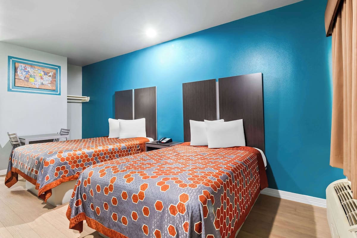 A hotel room with two beds, a desk, and a chair.